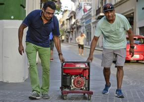 Residents roll a portable generator through the streets of San Juan